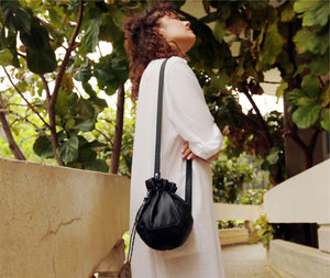 This black leather bucket bag is a must-have for any fashion-savvy individual, crafted in premium soft Italian Napa leather with an adjustable & detachable matching leather strap. Featuring a drawstring tie closure and woven lining. This style is versatile and can be carried as a shoulder or crossbody bag with strap or as a wristlet clutch by the drawstring.