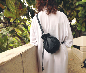 This black leather bucket bag is a must-have for any fashion-savvy individual, crafted in premium soft Italian Napa leather with an adjustable & detachable matching leather strap. Featuring a drawstring tie closure and woven lining. This style is versatile and can be carried as a shoulder or crossbody bag with strap or as a wristlet clutch by the drawstring.