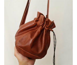 This cognac brown leather bucket bag is a must-have for any fashion-savvy individual, crafted in premium soft Italian Napa leather with an adjustable & detachable matching leather strap. Featuring a drawstring tie closure and woven lining. This style is versatile and can be carried as a shoulder or crossbody bag with strap or as a wristlet clutch by the drawstring.
