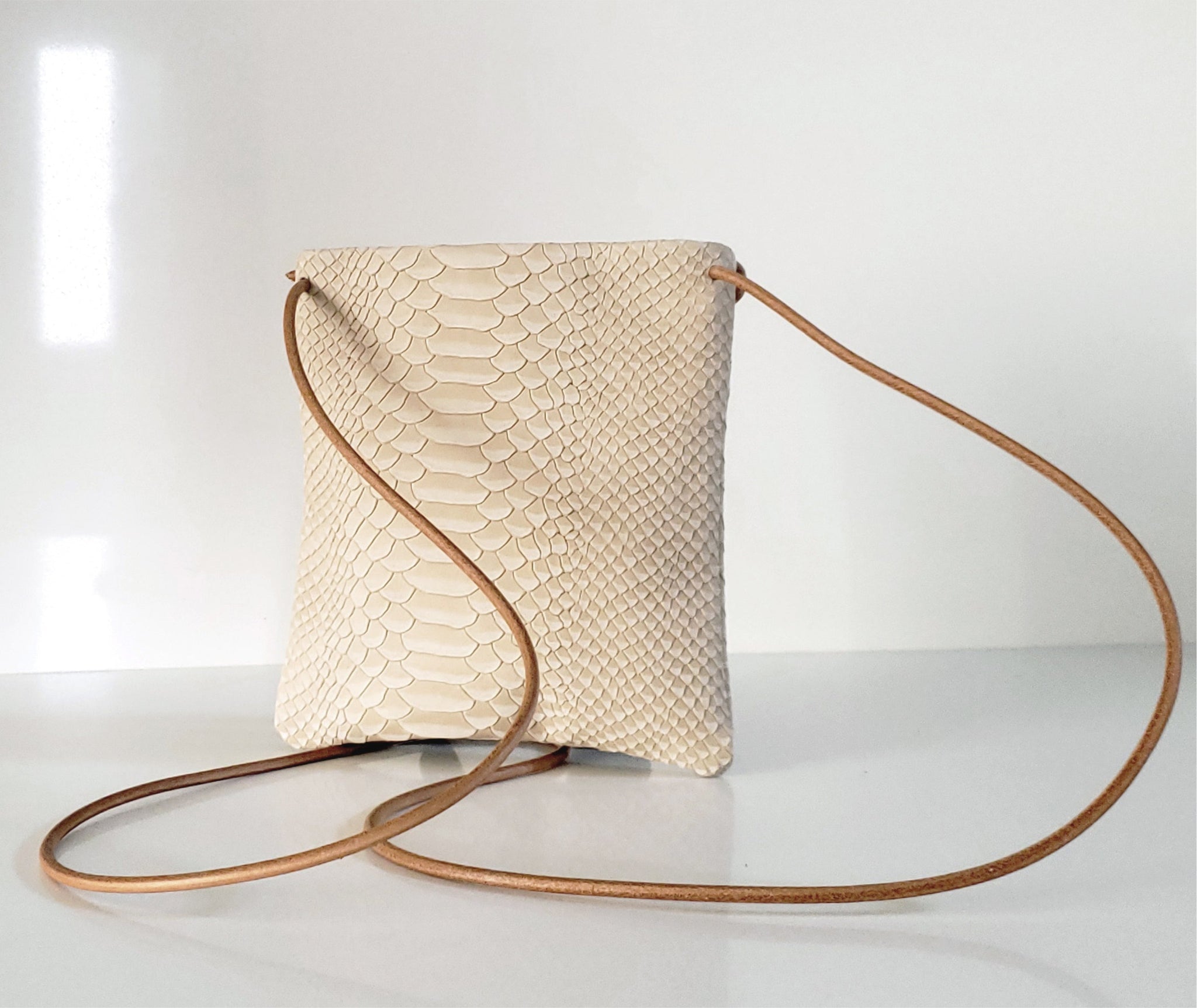 This handmade small leather shoulder bag is crafted with rich python-embossed soft Italian leather, and a round-shaped adjustable & detachable natural tan leather strap. Its high-end finish yet effortless look works night or day and fits cellphones, keys, cash, cards, lipstick, and more. It can be carried as a crossbody shoulder bag, or as an evening clutch without the strap.  