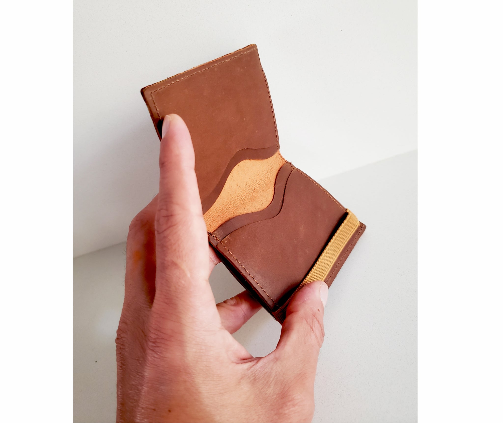 Brown Handmade Italian leather bifold wallet. The perfect lightweight slim wallet to fit seamlessly in your pocket. This cards wallet features a coin pocket, and secure rubber band & metal clip for bills.